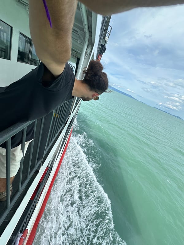 Leaning over a ferry railing in turquoise Thai waters