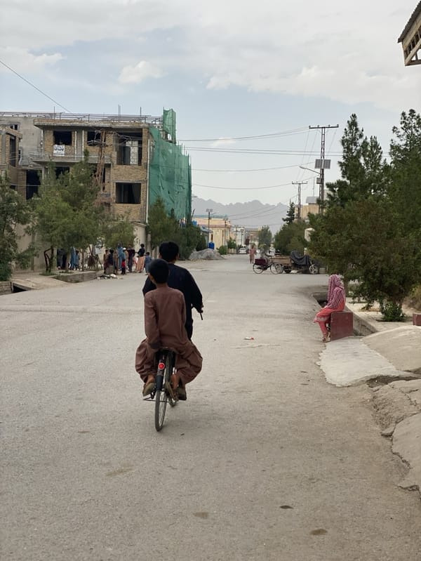 Two boys share bicycle ride on Kandahar street
