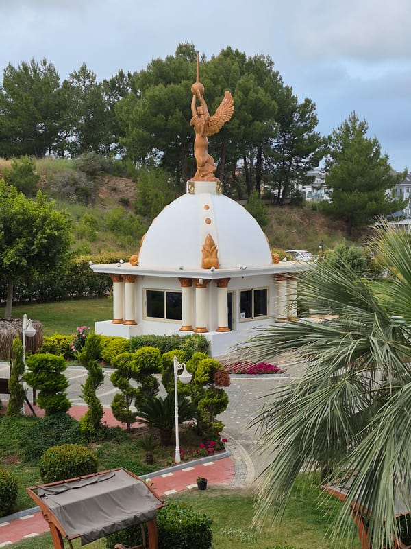 Building with golden winged statue, garden documented in Alanya