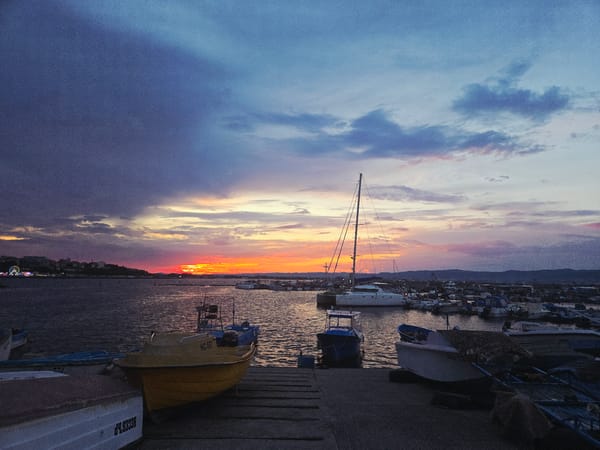 Dusk settles over a harbor marina with abstract sculpture