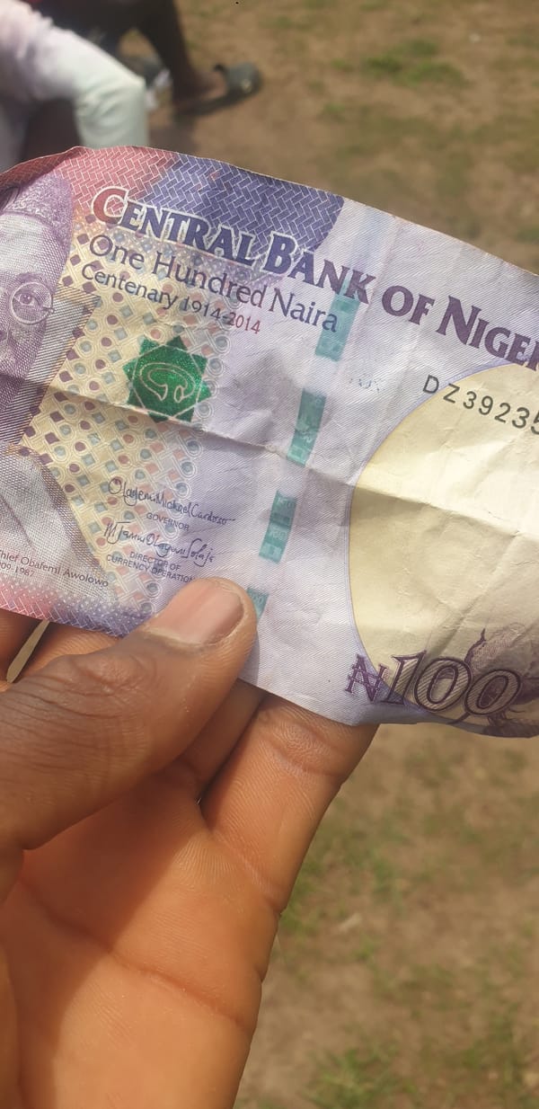 Person holds Nigerian centennial 100 Naira banknote