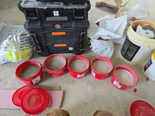 Construction materials and buckets documented on concrete floor