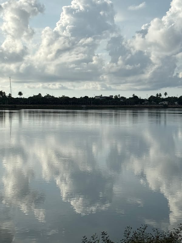 Cloudy sky reflects in Thai waterway near populated area