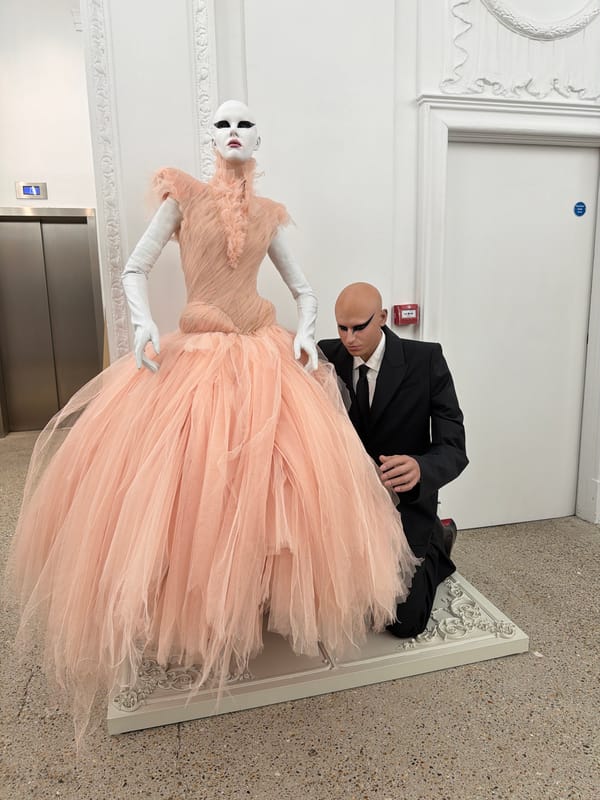 Man adjusts formal mannequin display in London clothing store