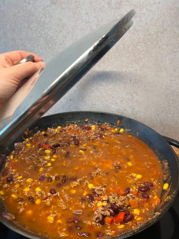 Person prepares chili with beans, corn in German kitchen