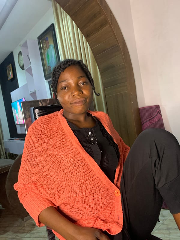 Indoor portrait session in Jos, Nigeria — coral cardigan and braids