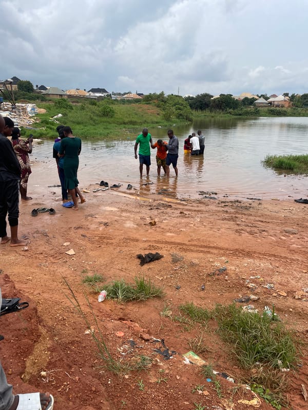 Outdoor baptism service in muddy water near Jos, Nigeria