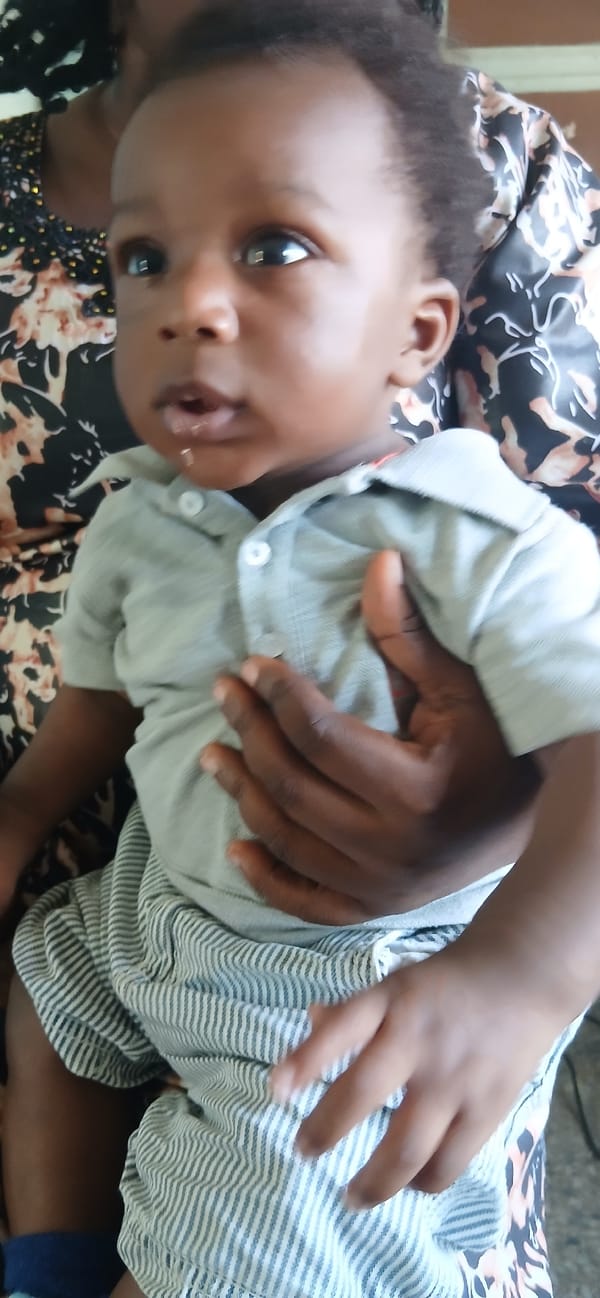 Woman holds baby while man stands in doorway, Shaba Nigeria