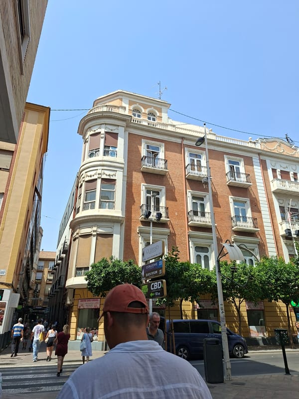 Grand curved facade anchors a busy Murcia street scene