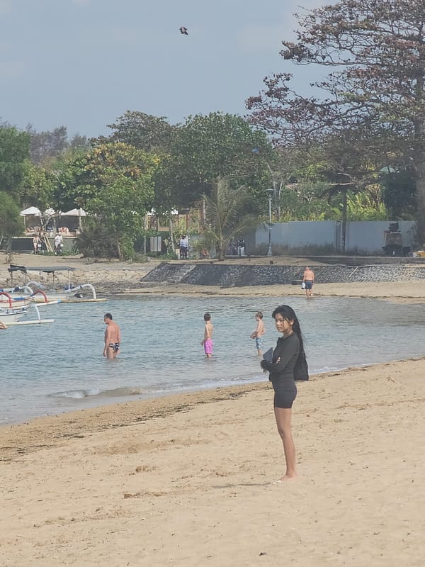 Busy Denpasar beach with boats anchored just offshore
