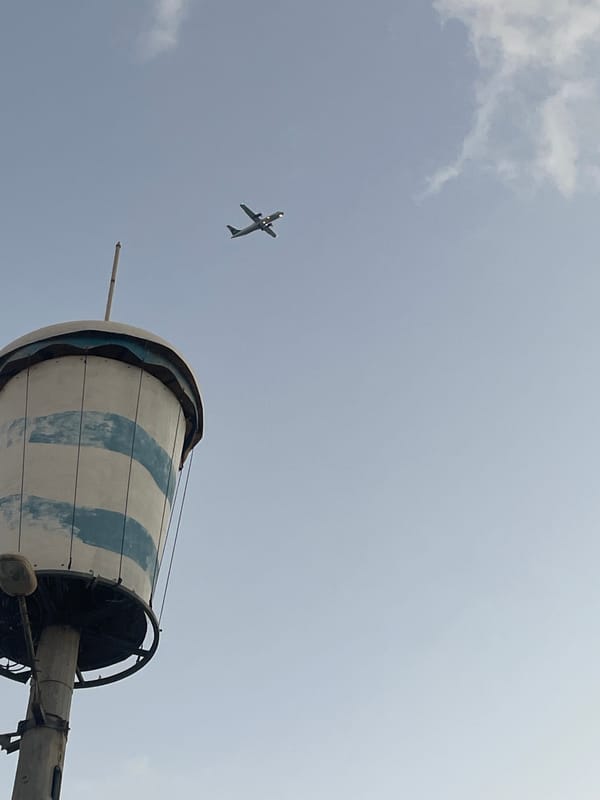 Turboprop crosses cloudy skies over Kiryat Yam's coastal streets at dusk