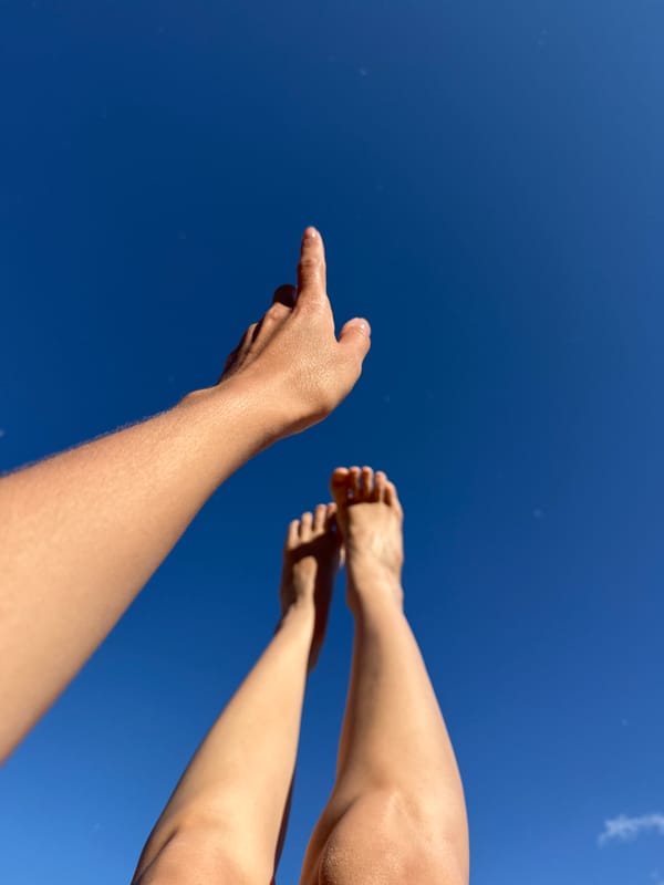 Limbs reaching skyward in a bright blue-sky moment