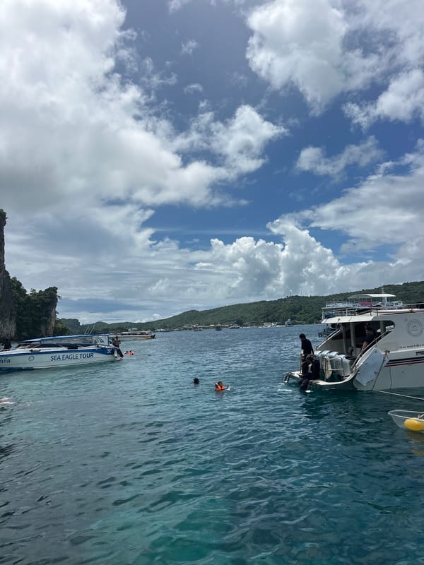 Boats and snorkelers at Haad Hin Khom's limestone coast
