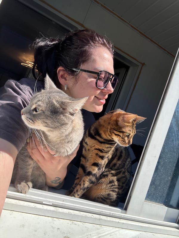 Woman poses with cats while rats rest in cages