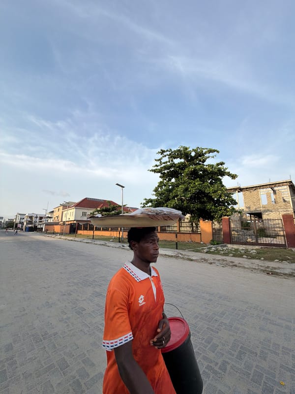 Man carries containers on head through Igboefon street