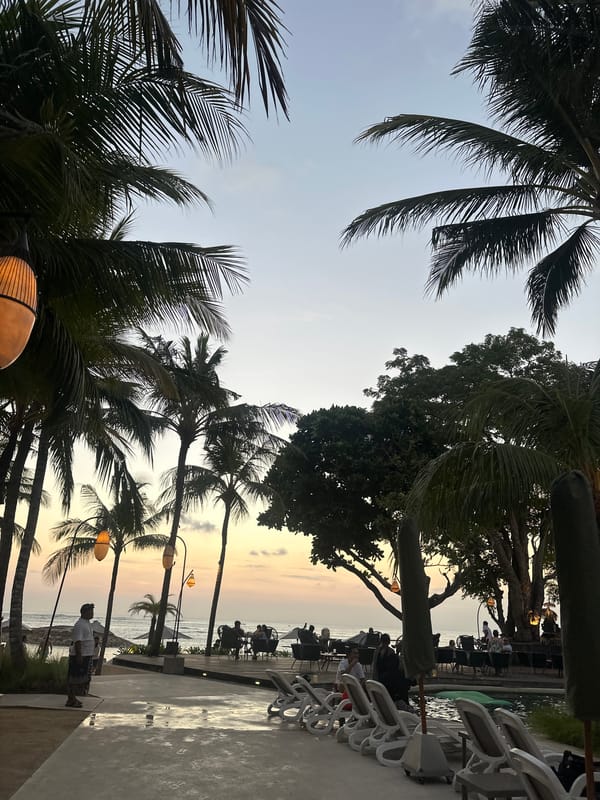 Dusk at a Kuta resort: pools, palms, and beachfront.