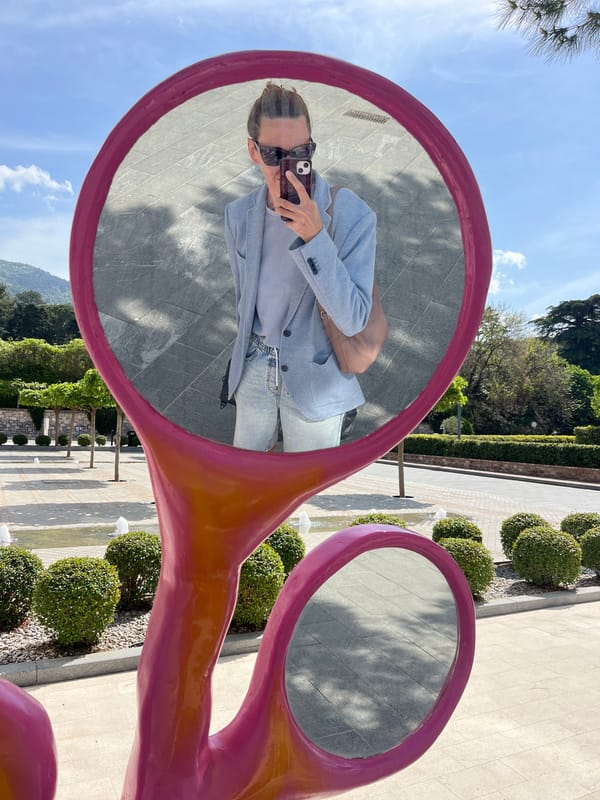 Tourist poses in pink mirror scissors sculpture in Tivat