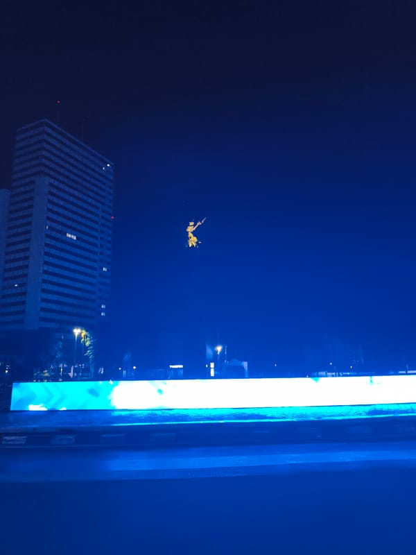 Nighttime urban traffic flows past illuminated commercial buildings