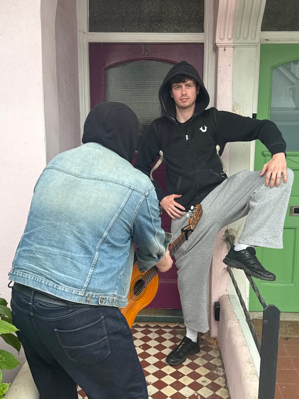 Two people with guitar sit on Brighton building steps
