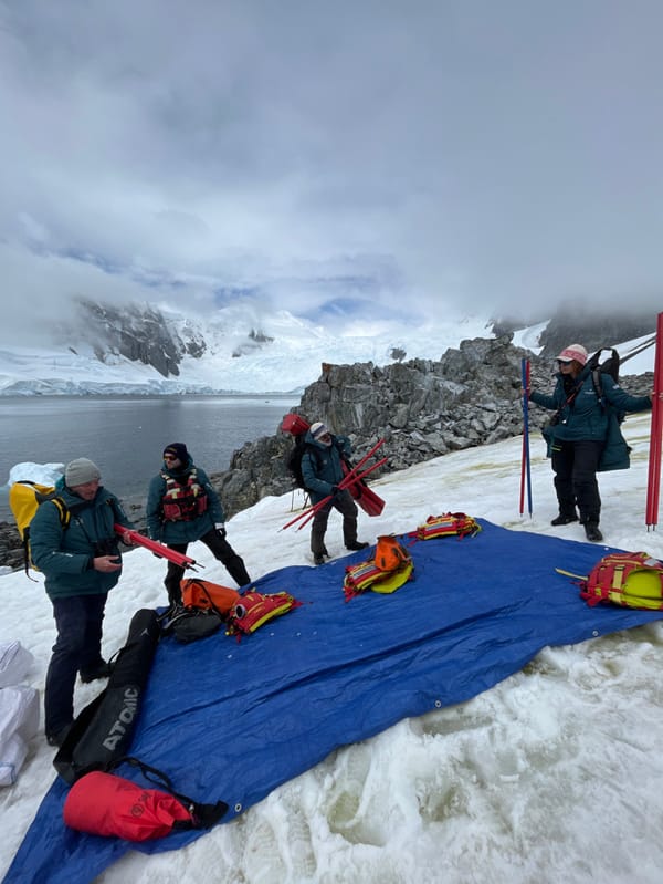 Group explores Antarctic coastline with inflatable boat near glacial waters