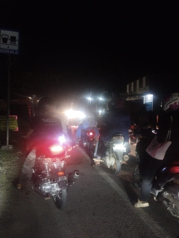 Motorcycles line up on congested Lhokseumawe street at night