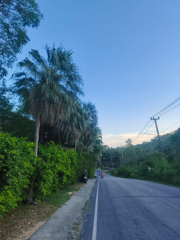 Clear skies over tree-lined road in Choeng Mon, Thailand