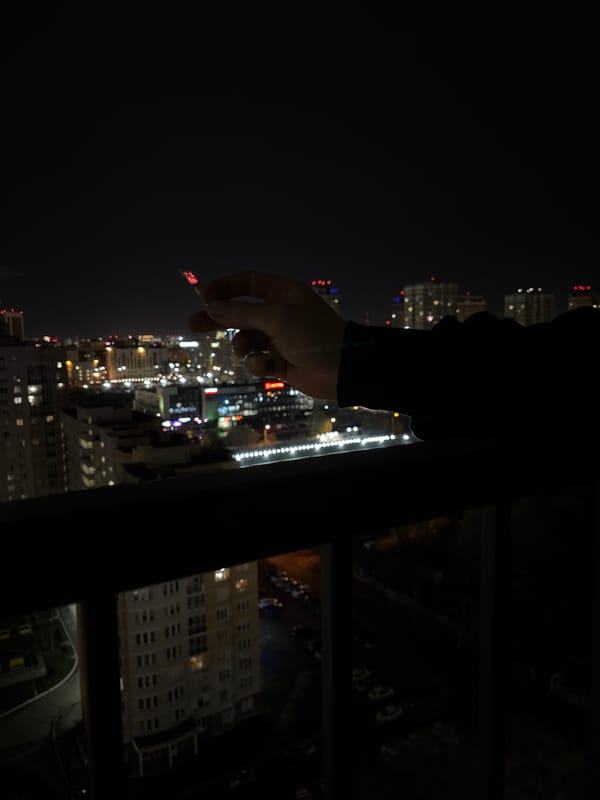 Person smokes overlooking Yekaterinburg cityscape at night
