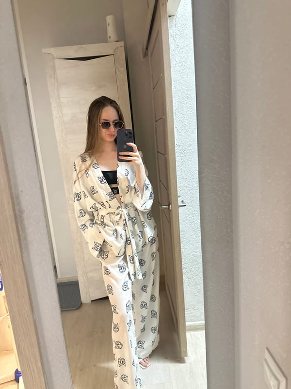 Woman documents waterfront outing in cat-patterned robe during dusk