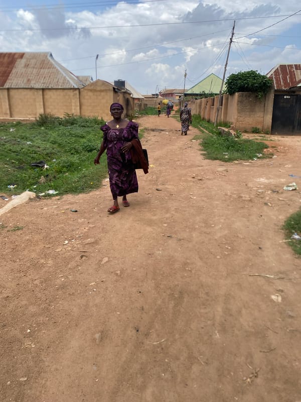 Woman carries bundle on dirt road in Bukuru
