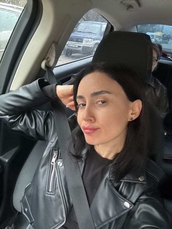 Woman makes peace sign in car during rain in Tbilisi