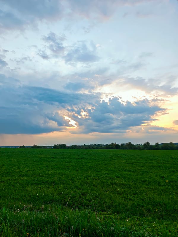 Sunlight breaks through clouds over green field in Yakhroma