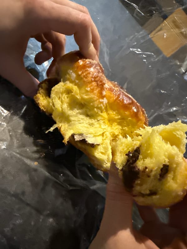 Person breaks open glazed pastry in Great Yarmouth
