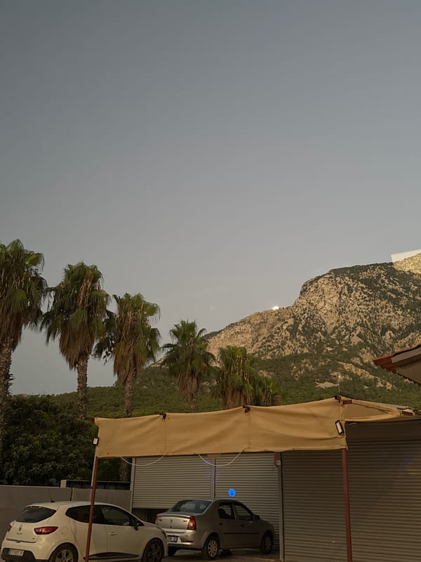 Late-night Kemer: moon over mountains, palms, and quiet streets
