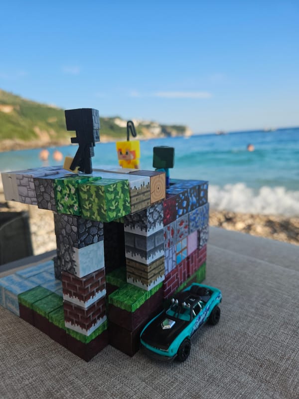 Relaxed pebble beach day with drinks, boats, and Minecraft toys