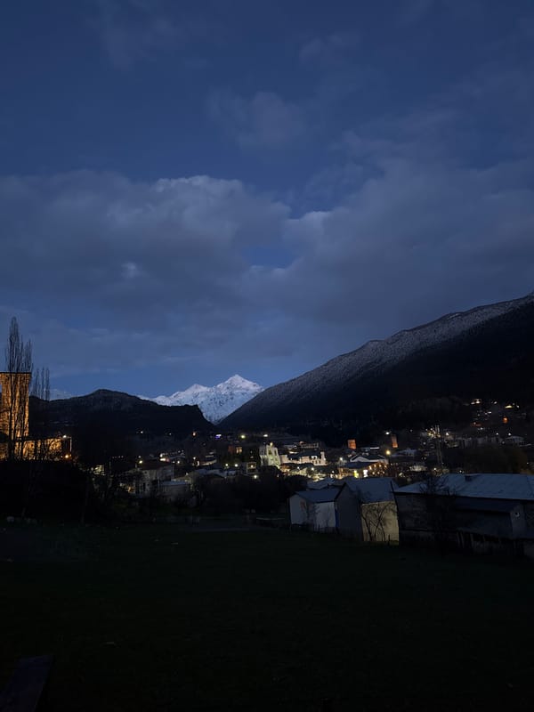 Moonlit snow peaks illuminate Mestia town at night