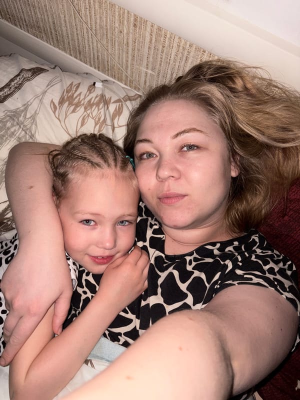 Woman and child rest together on bed in Noviy