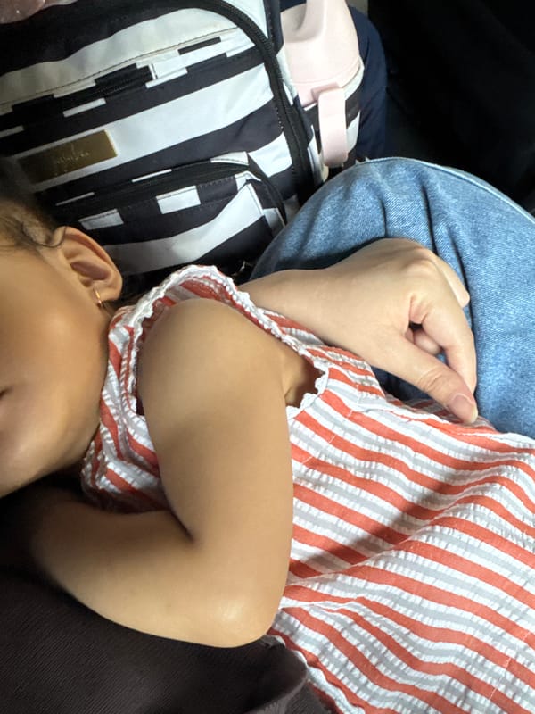 Child sleeps on lap in South Jakarta