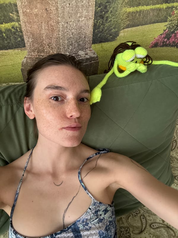 Person rests on green pillow with crochet toy nearby