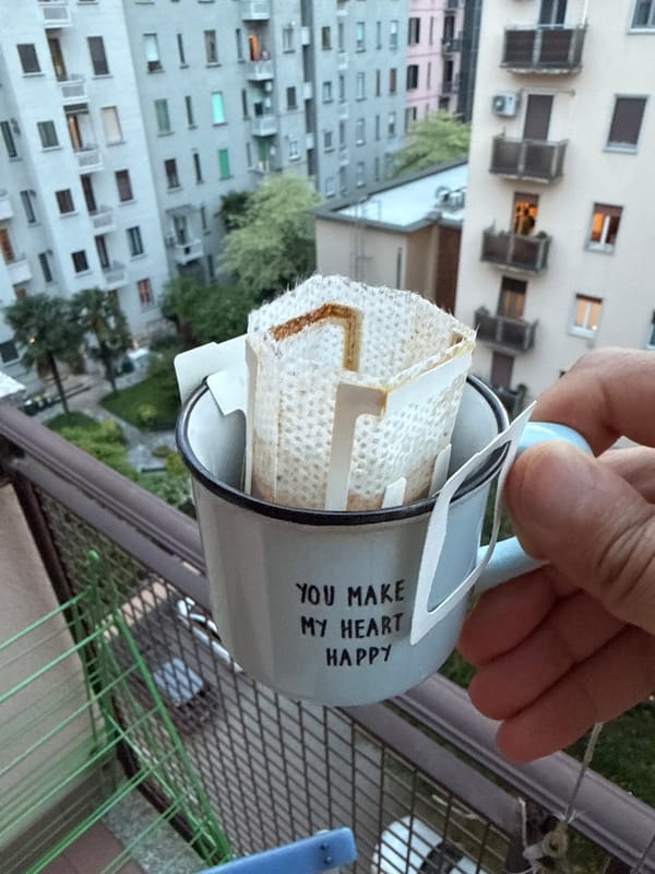 Person holds coffee mug with used filter on Milan balcony