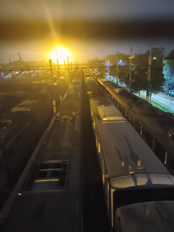Depok train yard at night, viewed through the fence