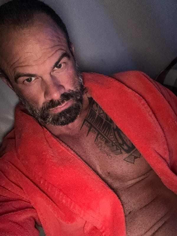Man in orange bathrobe filmed reclining indoors in Belgium