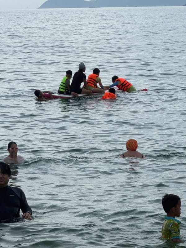 Busy morning at Nha Trang beach, ocean full and promenade humming