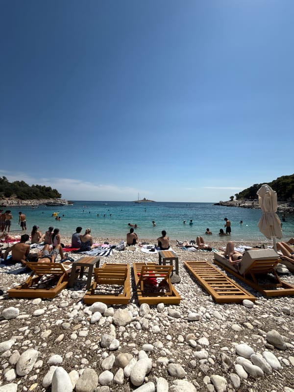 Hvar beach afternoon: swimmers, sailboats, and a lighthouse island