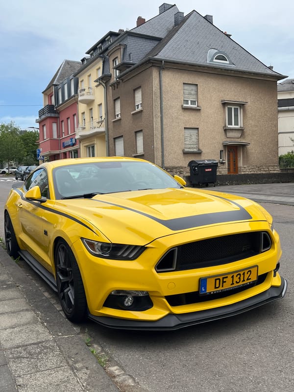 Yellow Ford Mustang with racing stripes parked in Luxembourg City