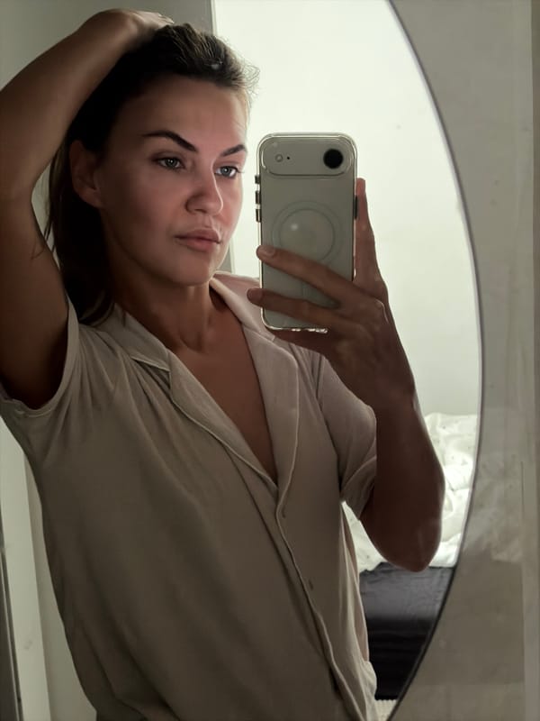 Mirror selfie and skincare bottle in a Holon bedroom