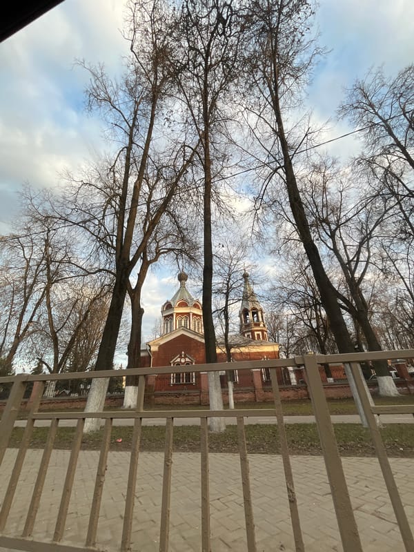 Red brick building photographed through fence in Klin, Russia