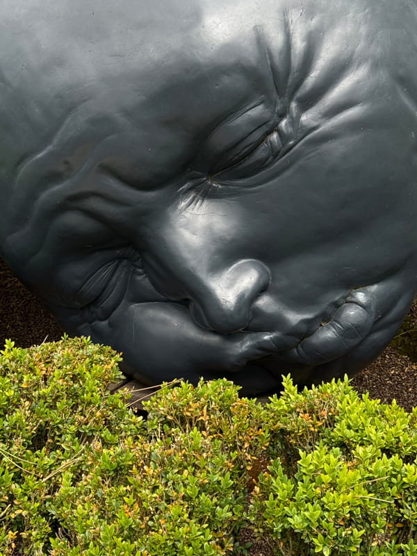 Sculptural faces emerge from manicured gardens overlooking Étretat cliffs