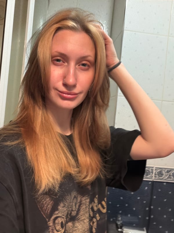 Bathroom mirror selfie session, black graphic tee, orange phone