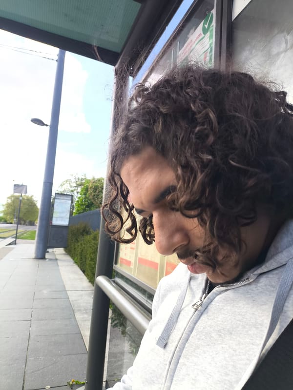 Person in grey hoodie waits at urban bus stop