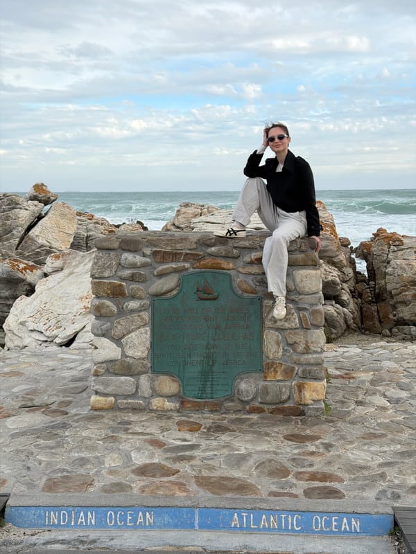 Tourist poses at stone monument in Cape Agulhas